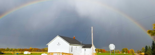 Rainbow over rural building and field