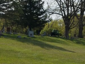 Cemetery with gravestones and green utility vehicle