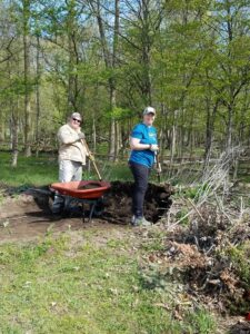 Two people gardening in a wooded area.