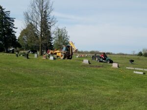 Cemetery maintenance with backhoe and golf cart.