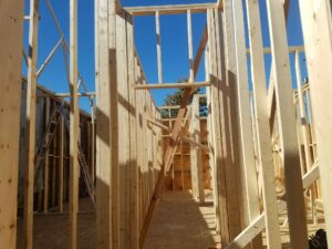 Wooden house frame under construction, sunny day.