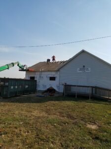 Workers repairing roof of township hall building.