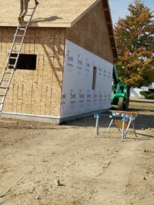 Construction site with worker on roof ladder.