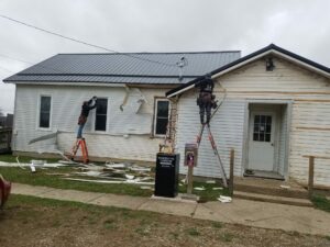 Workers removing siding from old house.