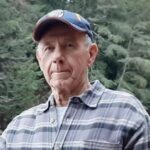 Man in plaid shirt and cap outside