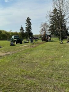 Workers operating machinery in a grassy field