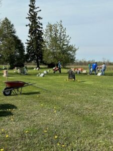 People working in a cemetery with wheelbarrow and tools.