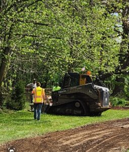 Workers operating machinery in a lush green park.