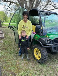 Smiling woman and child by an ATV outdoors.